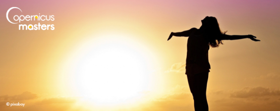 A woman silhouette standing in sunset with arms open wide