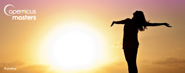 A woman silhouette standing in sunset with arms open wide